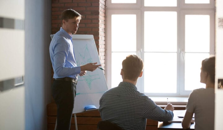 Man at work presents with white board to colleagues