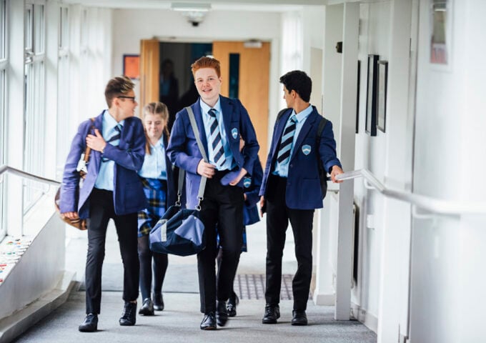 Small group of teenage school children walking through school corridor to their next class.