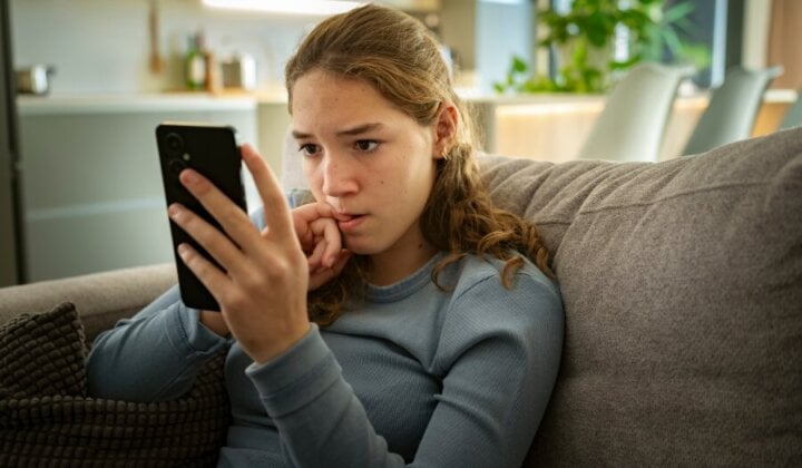 Young girl biting her nail looking at her mobile