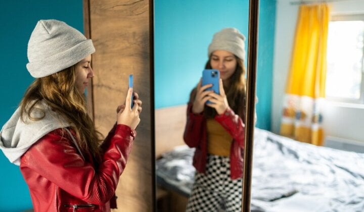 Young girl looking at herself in the mirror and taking a photo