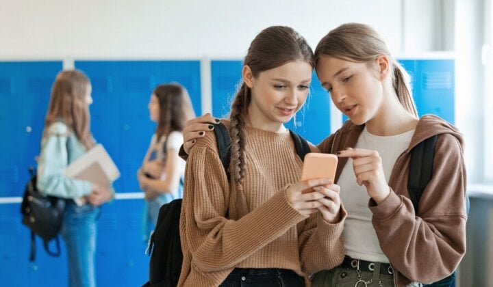 Two young girls talking about content on a mobile phone