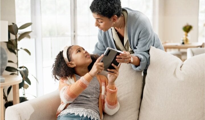 Young girl having her phone taken off her by her mother